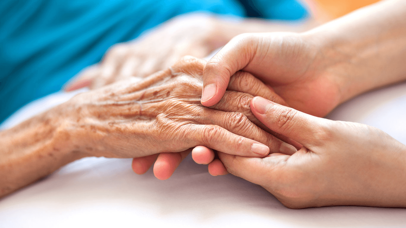 Caregiver holding an older patient’s hand